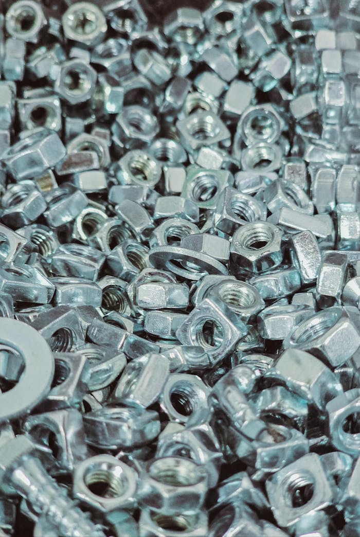 Close-up view of a pile of silver metal nuts and bolts with detailed textures.